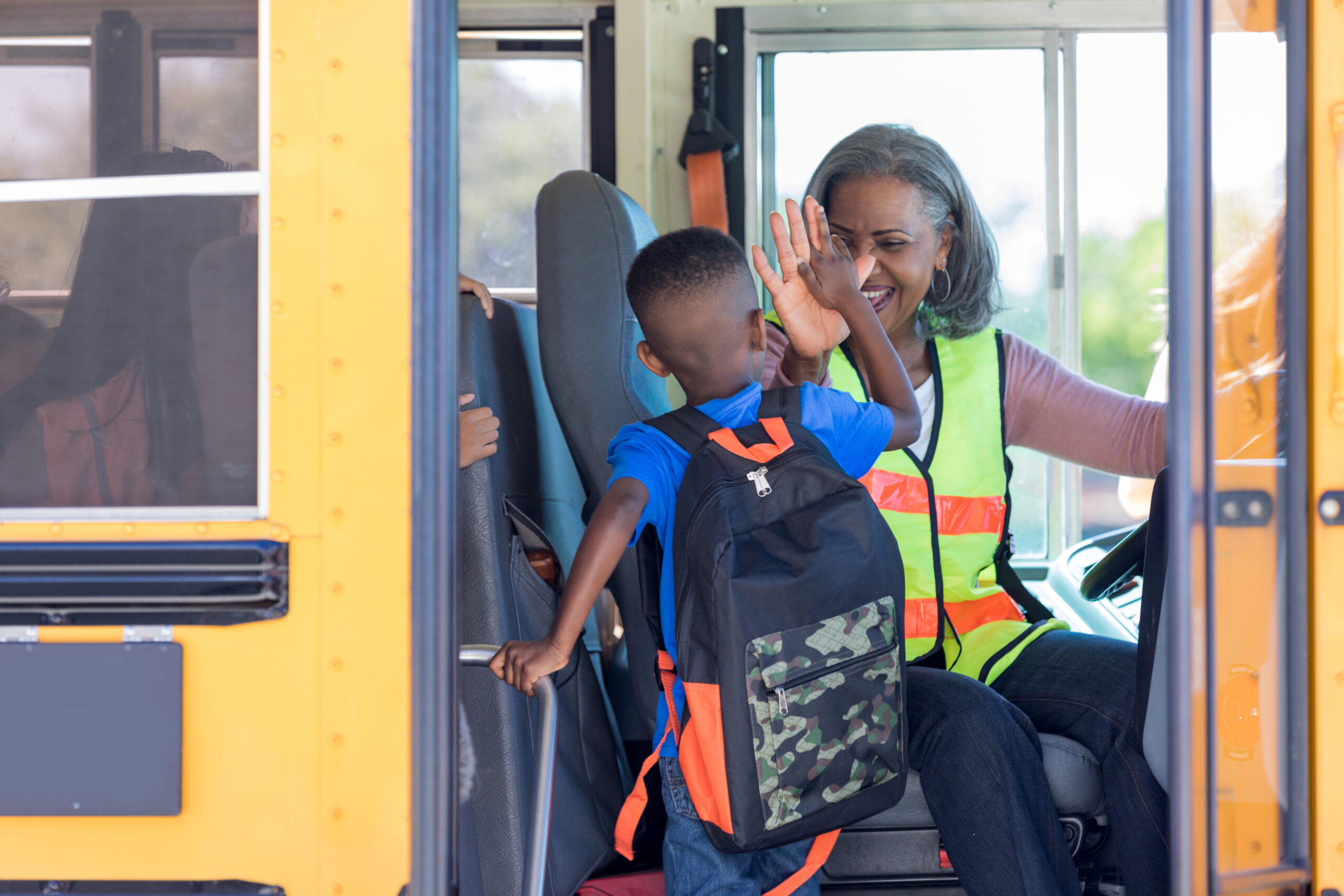 Bus driver high fives new student stepping on bus