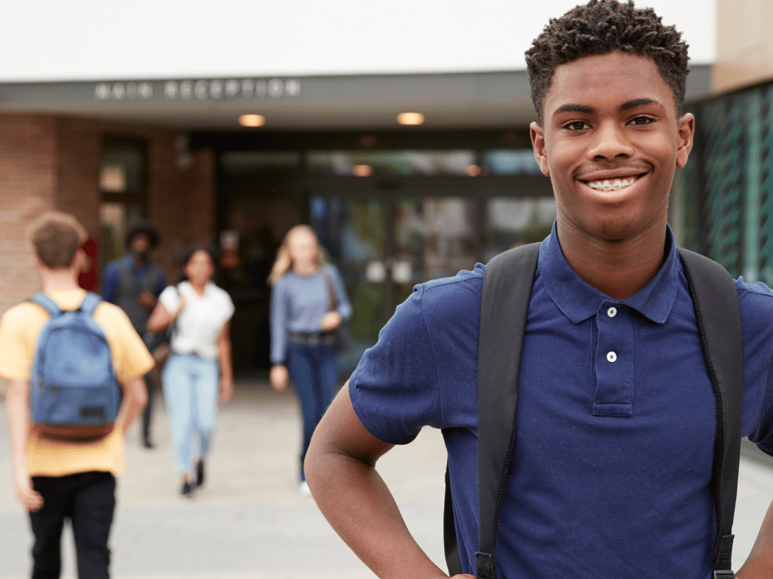 Young Black student outside the school building preparing for class