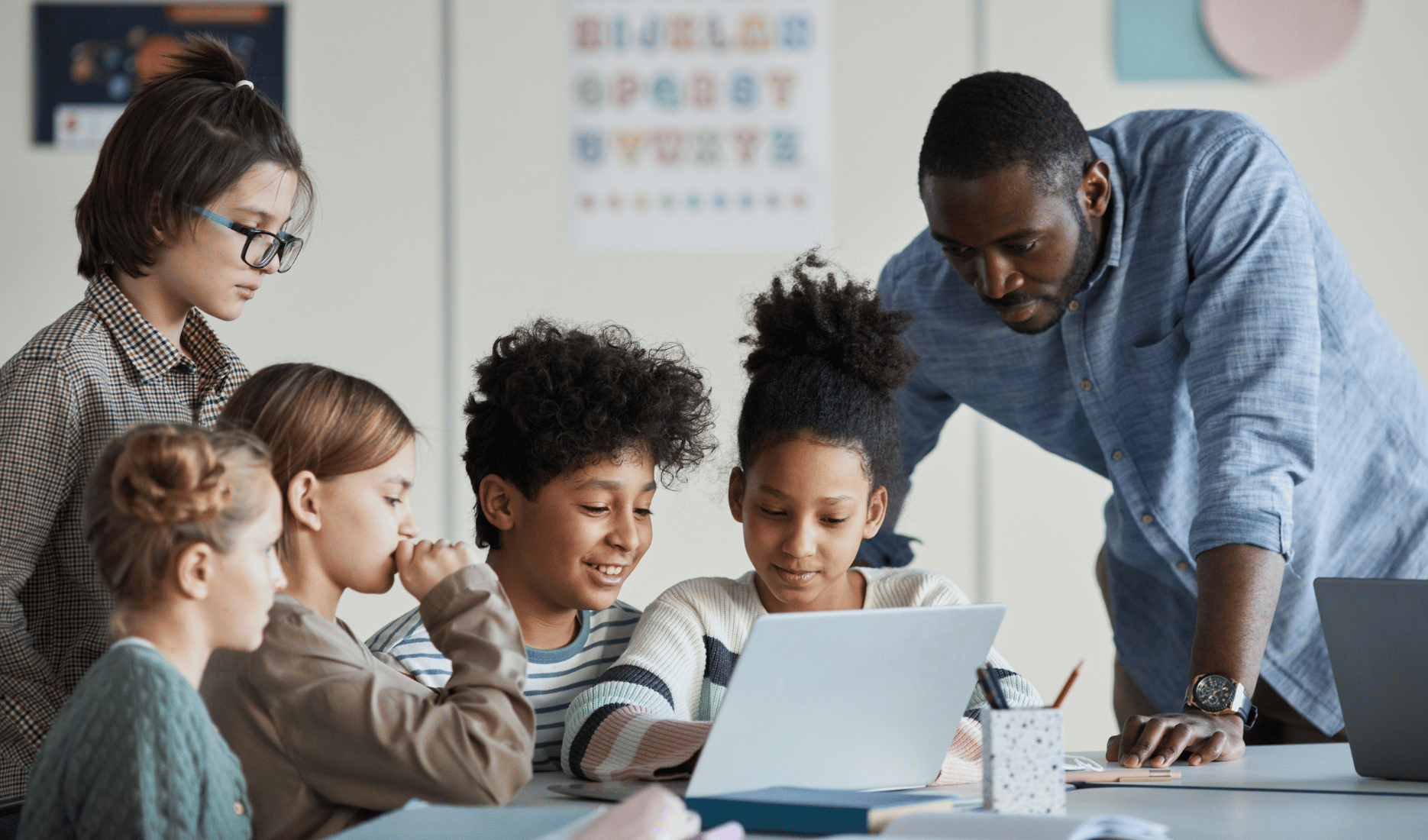 Black male teacher working with diverse group of students on a project