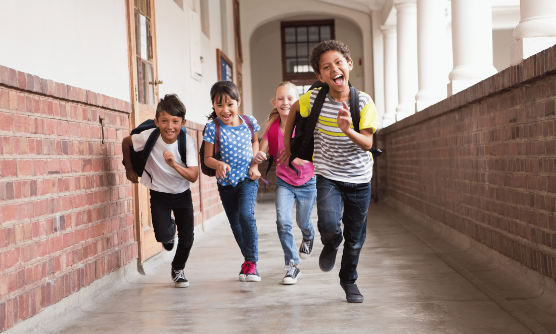 Group of young kids running through a school hallway